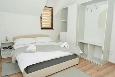 a white bedroom with a large bed and a mirror at Lola's House in Jajce