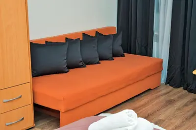 an orange couch with black pillows in a bedroom at Lola's House in Jajce
