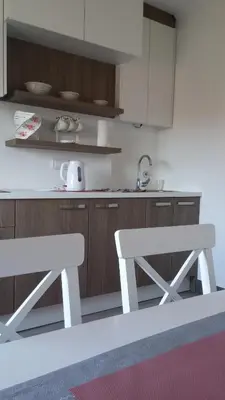 a kitchen with white cabinets and a table and chairs at Stan-apartman A&A in Banja Luka