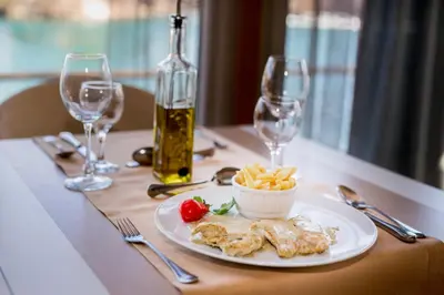 a table with a plate of food and wine glasses at Hotel Opal Exclusive Bihać in Bihać