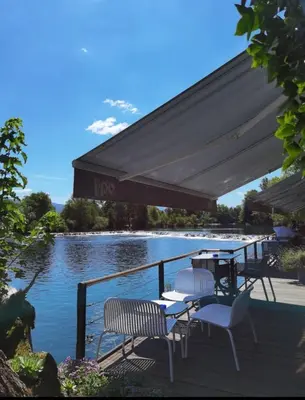 a patio with tables and chairs next to a body of water at Hotel Opal Exclusive Bihać in Bihać