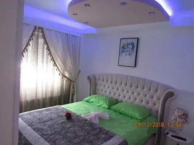 a bedroom with a bed with a white headboard and a ceiling at Apartman Tea 2 in Banja Luka
