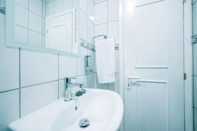 a white bathroom with a sink and a mirror at Apartman Luka in Livno