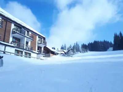 a building with snow on the ground in front of it at Vlašićka idila apartman Eko Fis 507 in Vlasic