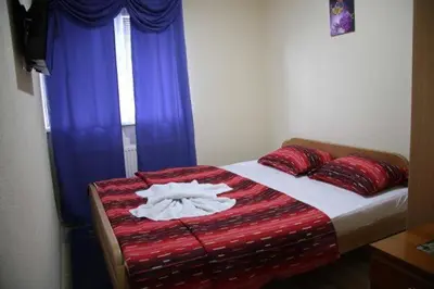 a bedroom with a bed with red and blue curtains at Apartmani Kadunić in Bugojno