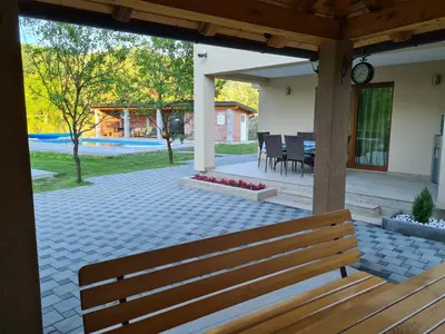 a wooden bench on a patio with a table and chairs at Oasis of peace in Bihać