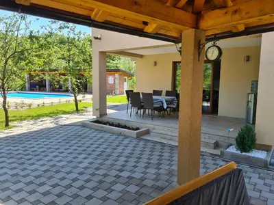 a patio with a clock and a table and chairs at Oasis of peace in Bihać