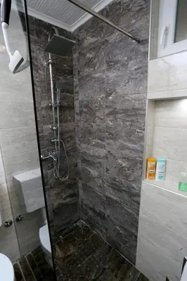 a bathroom with a shower with a stone wall at Apartman City Lux in Banja Luka