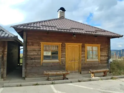 a log cabin with two benches in front of it at Apartment Panorama 1 in Vlasic