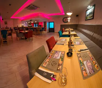 a restaurant with long tables and chairs and pink lighting at Motel Felikitas in Laktaši
