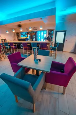 a dining room with a table and purple chairs at Motel Felikitas in Laktaši
