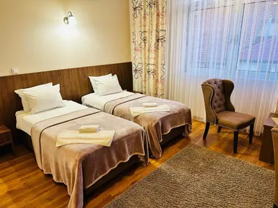 a hotel room with two beds and a chair at HOTEL MINERO in Tuzla
