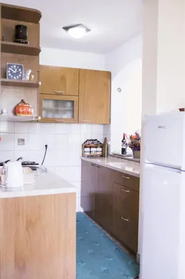 a kitchen with wooden cabinets and a white refrigerator at ENNI in Bihać