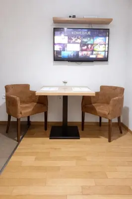 a table with two chairs and a tv on a wall at NM Apartman in Banja Luka