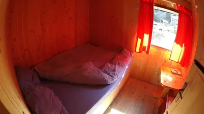 a small bed in a small room with a window at Koliba - Prokoško jezero in Fojnica