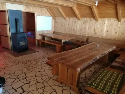 a room with a wooden table and a wood stove at Koliba - Prokoško jezero in Fojnica