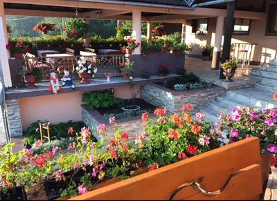 a garden with flowers and tables and chairs at Restoran sa sobama za iznajmljivanje MALI RAJ in Mrkonjić Grad