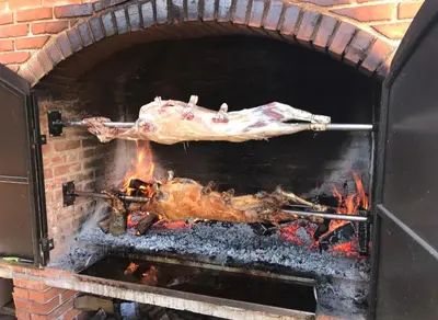 a piece of meat cooking in a brick oven at Restoran sa sobama za iznajmljivanje MALI RAJ in Mrkonjić Grad