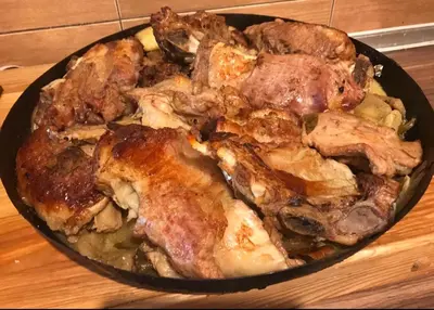 a pan filled with meat and vegetables on a table at Restoran sa sobama za iznajmljivanje MALI RAJ in Mrkonjić Grad