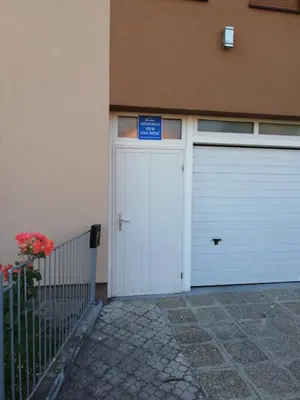 a white garage door with a blue sign on it at Apartman View Una in Bihać