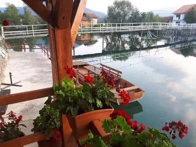 a boat on the water with flowers and a dock at Apartman View Una in Bihać