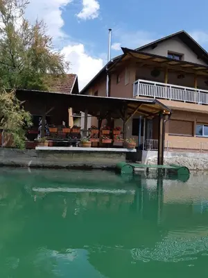 a house with green water in front of a building at Apartman View Una in Bihać