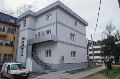 a white apartment building with a car parked in front at Prenoćište Park in Modriča