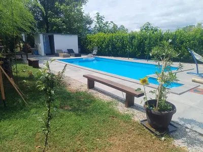 a swimming pool with a wooden bench in a yard at Holiday Home Edi in Bihać