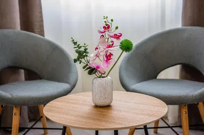 two chairs and a vase with flowers on a table at Grande Plus Apartment Dzungla in Doboj