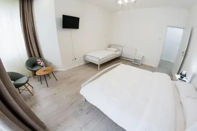 a living room with a white bed and a couch at Grande Plus Apartment Dzungla in Doboj