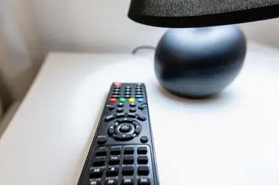 a remote control sitting on a table next to a lamp at Grande Plus Apartment Dzungla in Doboj