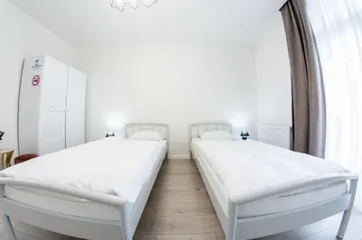 two beds in a room with white walls at Grande Plus Apartment Dzungla in Doboj