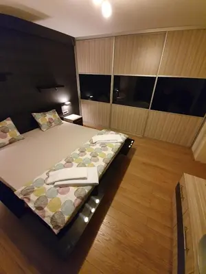 a bedroom with a large bed with a wooden floor at Apartman Marković in Bosanski Šamac