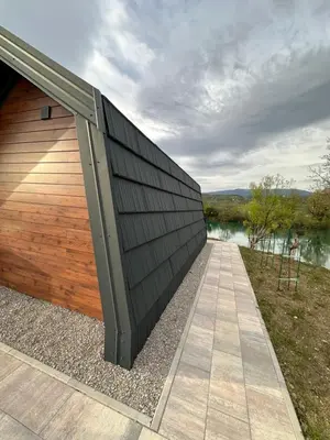 a building with a wooden fence next to a body of water at Apartments MLIN in Bihać