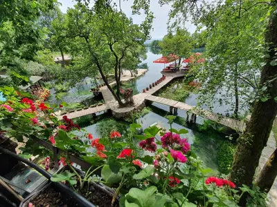 a view of a river with flowers and a bridge at Apartments MLIN in Bihać