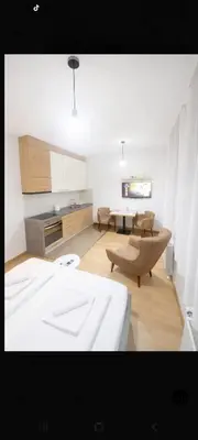 a living room with a white bed and a kitchen at NM apartman in Banja Luka