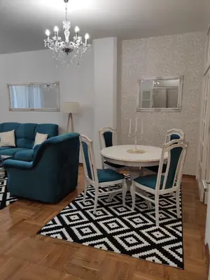 a living room with a blue couch and a table and chairs at Apartment Dajak Centar in Banja Luka