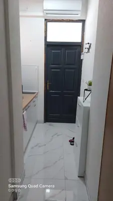 a kitchen with a black door and a white tile floor at Studio Apartman Malkoc in Bihać