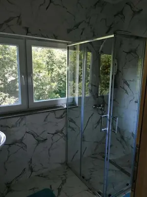 a bathroom with a glass shower with two windows at Sam guest house in Jajce
