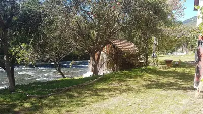 an old building next to a river with a tree at Sam guest house in Jajce