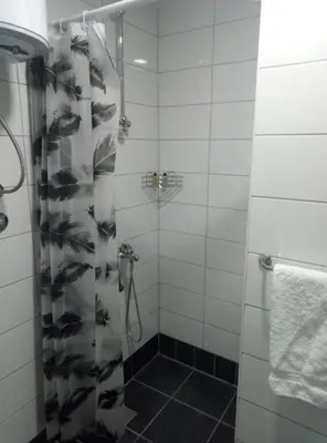 a shower with a glass door with fishes on the shower curtain at Apartments&Rooms Mido in Visoko