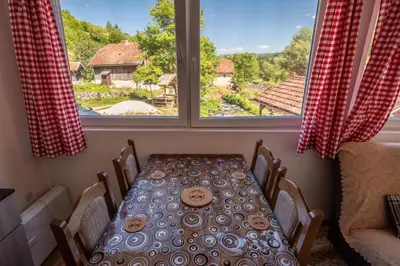a table and chairs in a room with a window at Domacinstvo na kraju svijeta in Šipovo