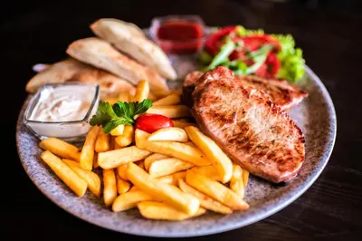 a plate of food with french fries and meat at Hotel Le Pont in Prijedor