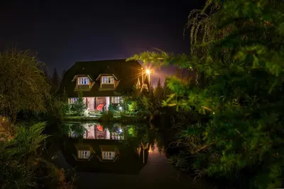 a house with a light on the water at night at Etno Village Cardaci in Vitez