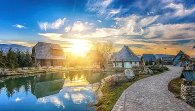 a view of a river with buildings and the sunset at Etno Village Cardaci in Vitez