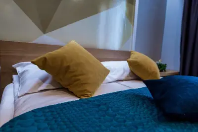 a bed with yellow pillows and a blue blanket at Hotel Safir in Bihać
