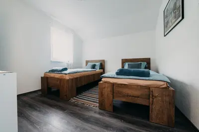 two twin beds in a room with wooden floors at Apartman Ena in Bihać