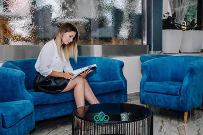 a woman sitting on a couch reading a book at Hotel Vezir Palace in Travnik
