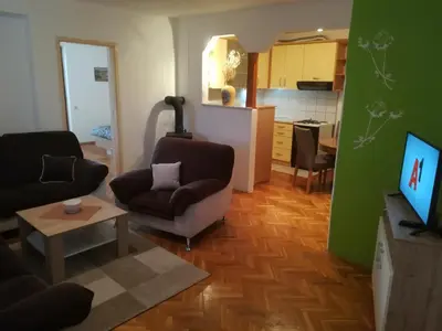 a living room with two chairs and a kitchen at Apartman Lidija in Livno