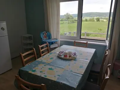 a dining room table with a table and chairs and a window at River Bank Apartments & Castle view in Bihać